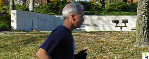 Photo of Ken Baldwin running past the Vietnam War Memorial at the KU Vets Day 5K and link to Flickr slideshow.