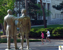Photo of two runners going by the Uncle Jimmy Green statue at the Race Ipsa 5K on April 14th.