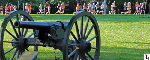Photo of the Battle of Westport cannon at Loose Park with runners on 55th Street in the background.