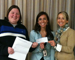 Photo of Heather Krase-Minnick presenting the runLawrence check to the Deerfield principal and PTo president for the school's Marathon Club.