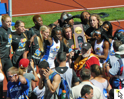 Photo of the KU Women's Track & Field Team singing the alma mater with their championship trophy in Eugene, OR.